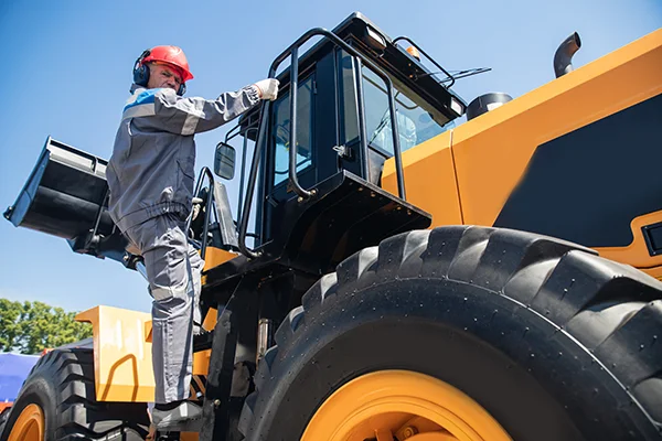 Man climbing into front loader.