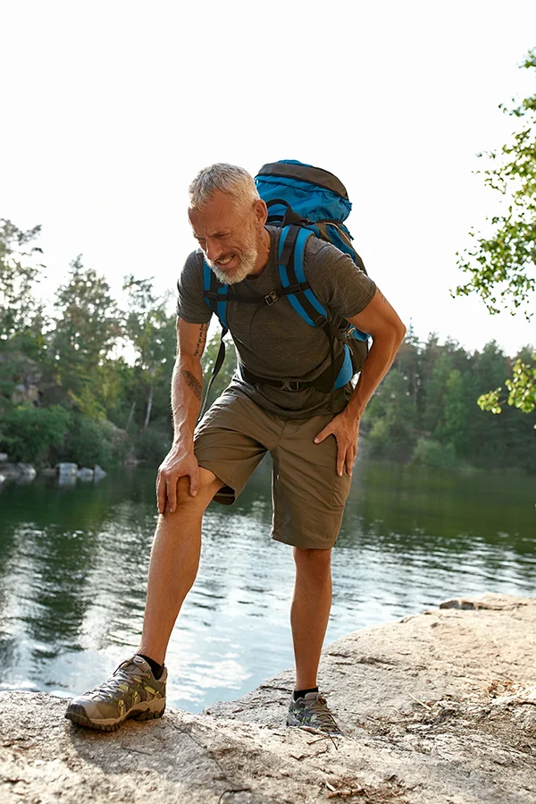 Man hiking, grabbing knee.