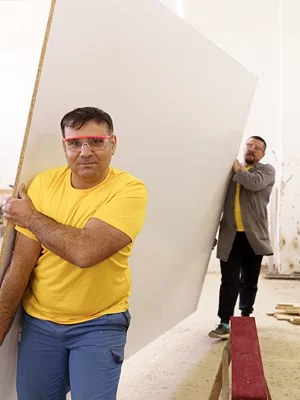 Two men carrying plywood. 